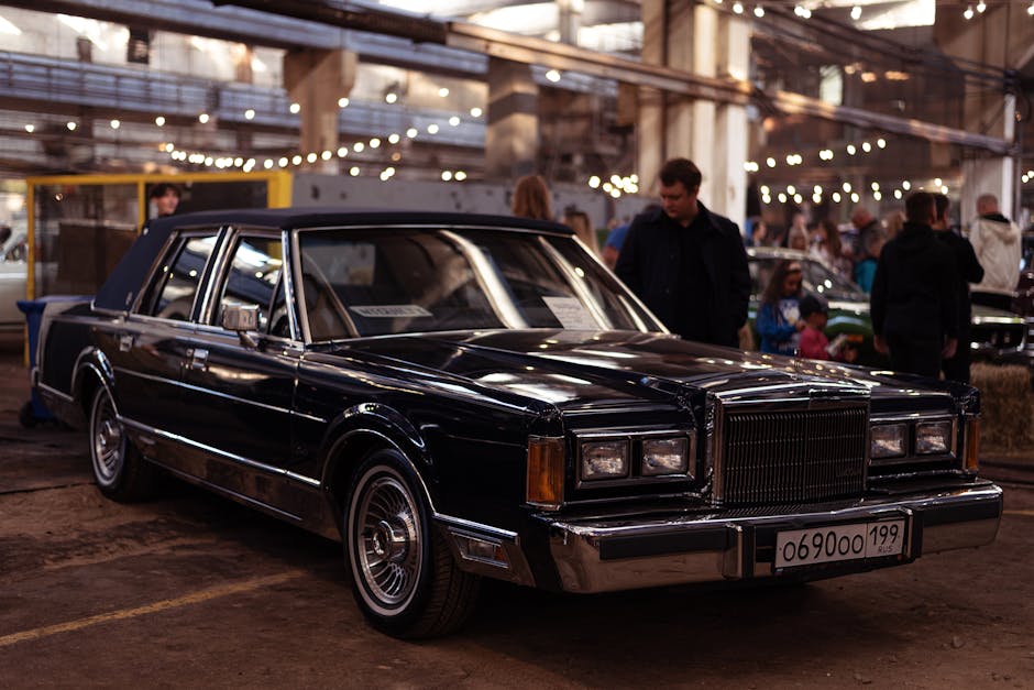 Vintage black luxury car showcased at an indoor car exhibition with stylish lighting.