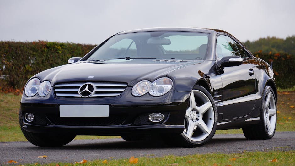 Shiny black Mercedes convertible on an outdoor road in daylight, showcasing luxury and design.
